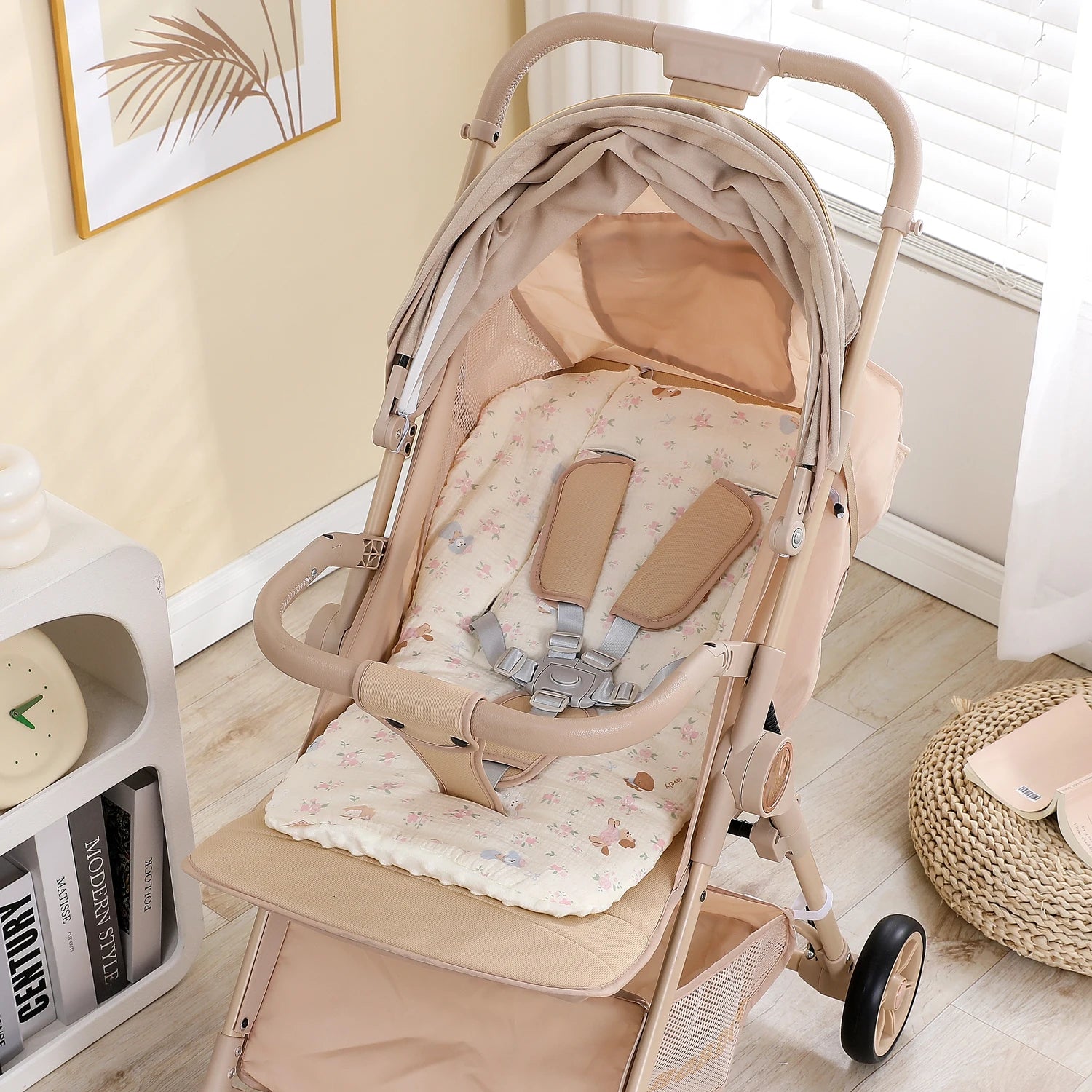 Beige baby stroller with a soft, floral-patterned cotton and polyester seat cushion and safety harness.