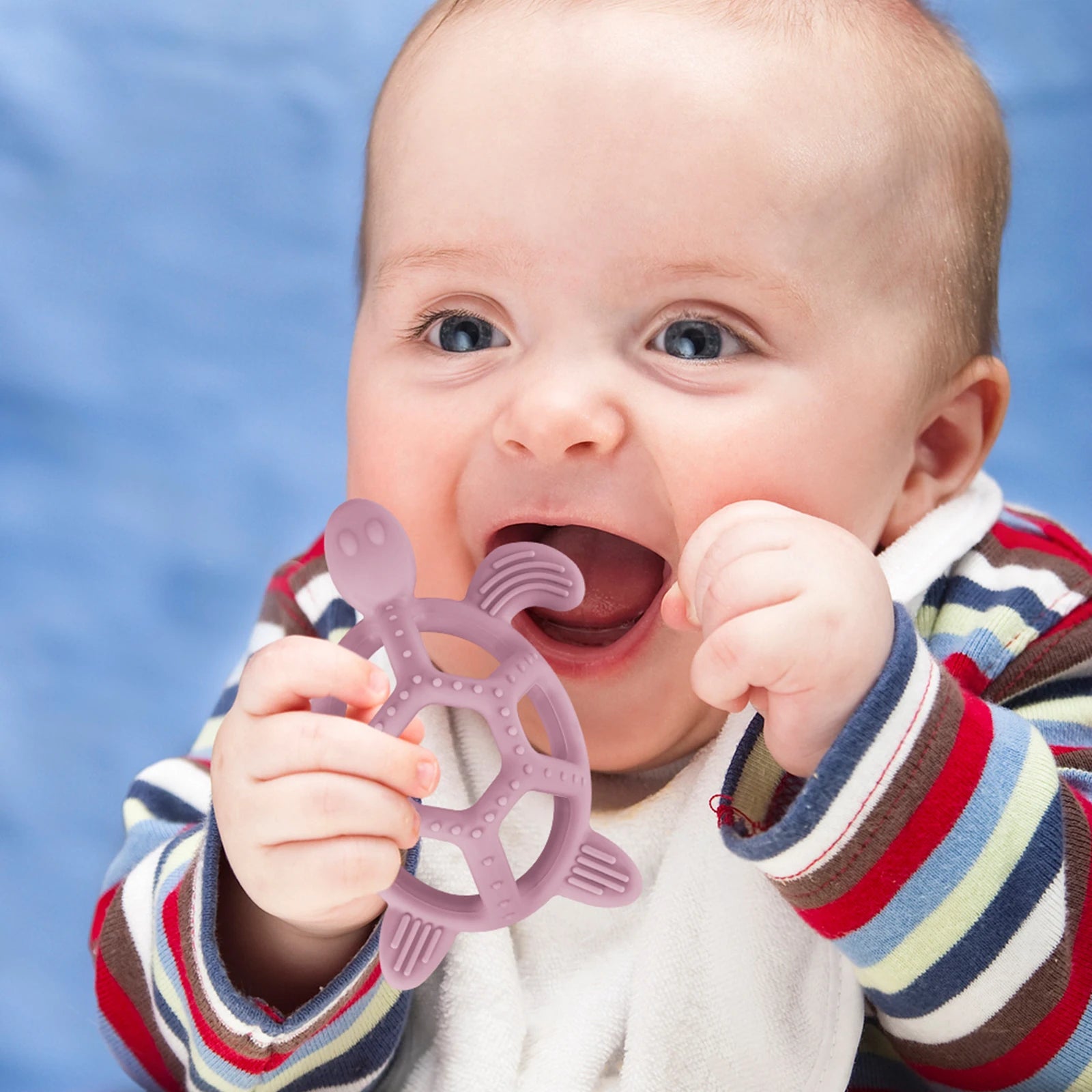 Happy baby holding a purple silicone turtle teether, designed for soothing gums.