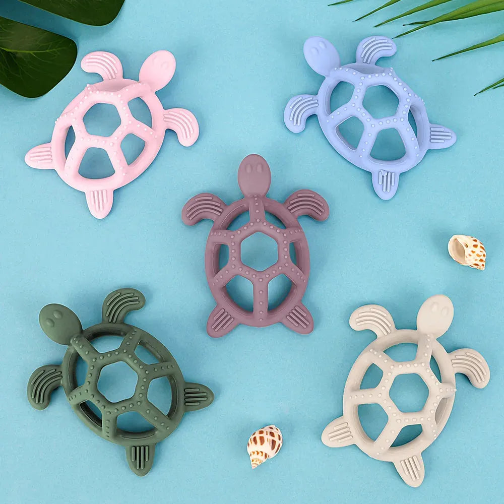 Five colorful silicone turtle teethers in pink, blue, purple, green, and beige on a blue background.