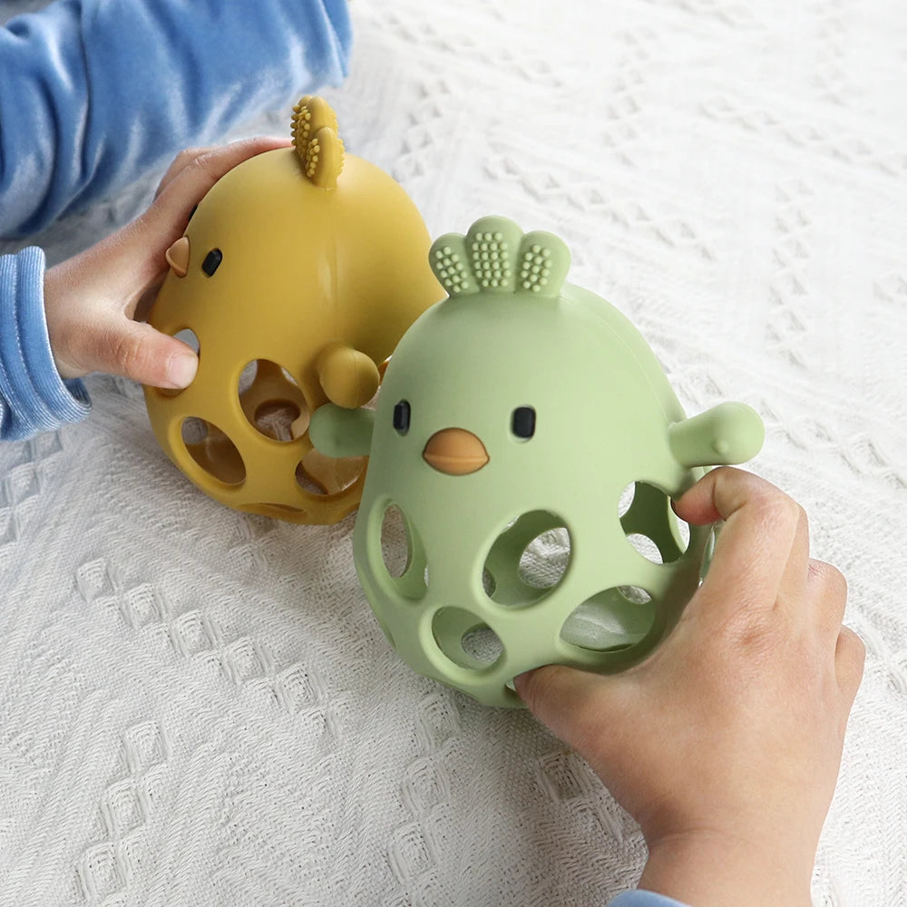 Two soft silicone chick teethers, one yellow and one green, held by baby hands.