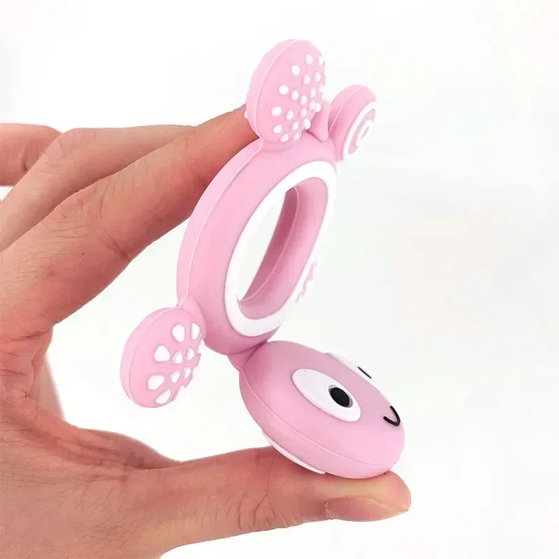 Pink silicone turtle baby teether held by a hand, featuring textured nubs for soothing gums.