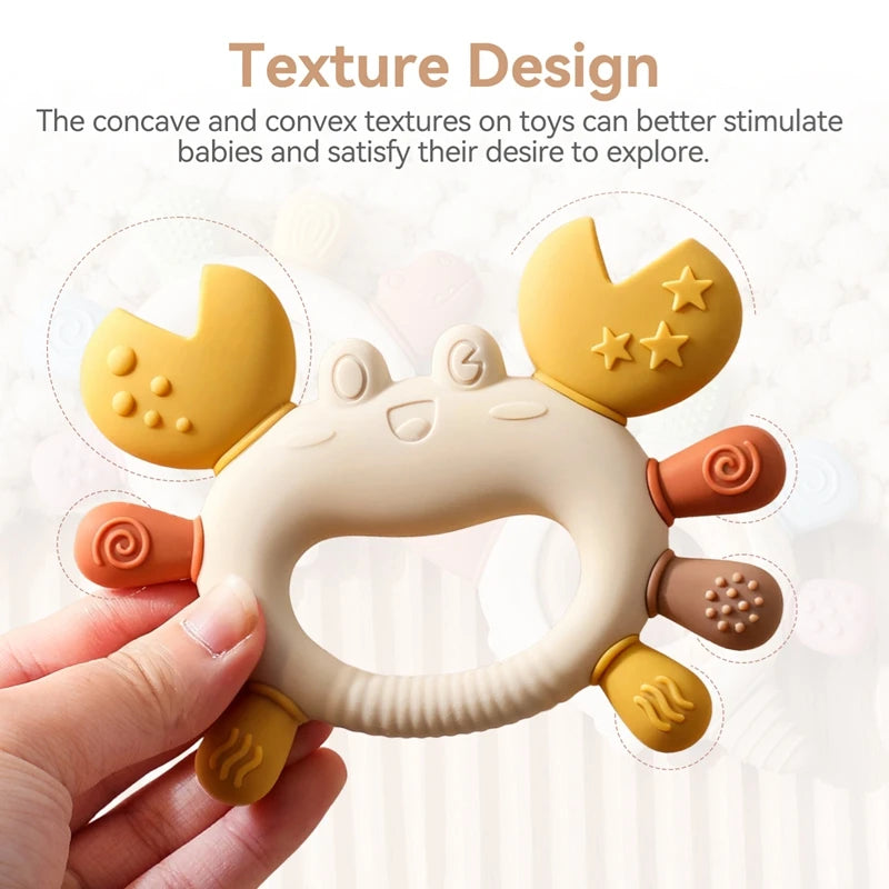 Crab-shaped silicone baby teether in beige, yellow, and orange with textured claws and legs for soothing gums.
