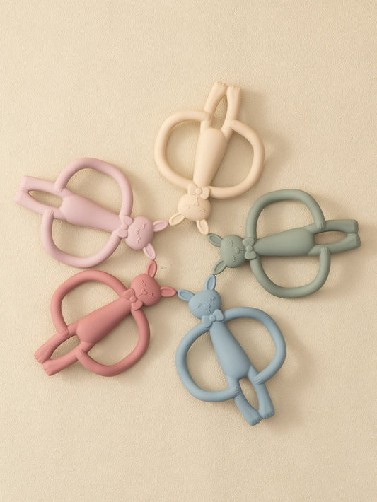 Soft silicone bunny teethers in pink, blue, green, peach, and beige, arranged on a light background.