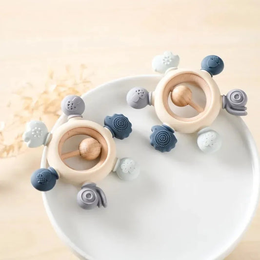 Montessori forest-themed baby silicone and wood teether rattles in muted blue, gray, and cream.
