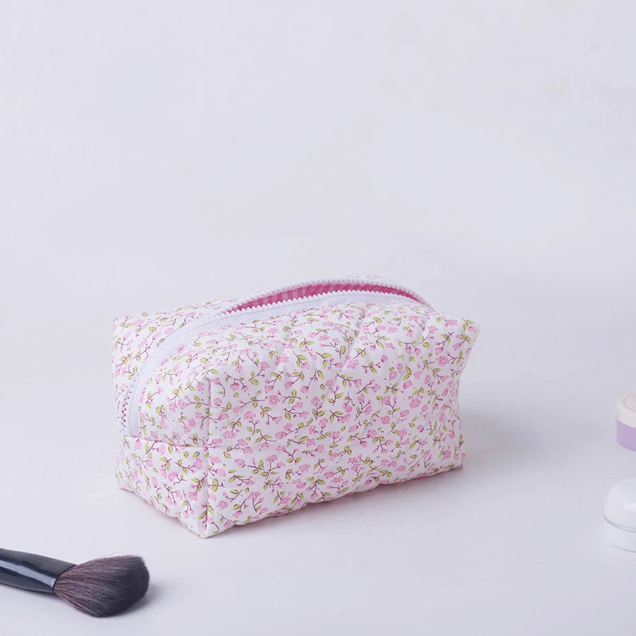 Pink floral padded makeup bag with white zipper, ideal for travel and daily use.