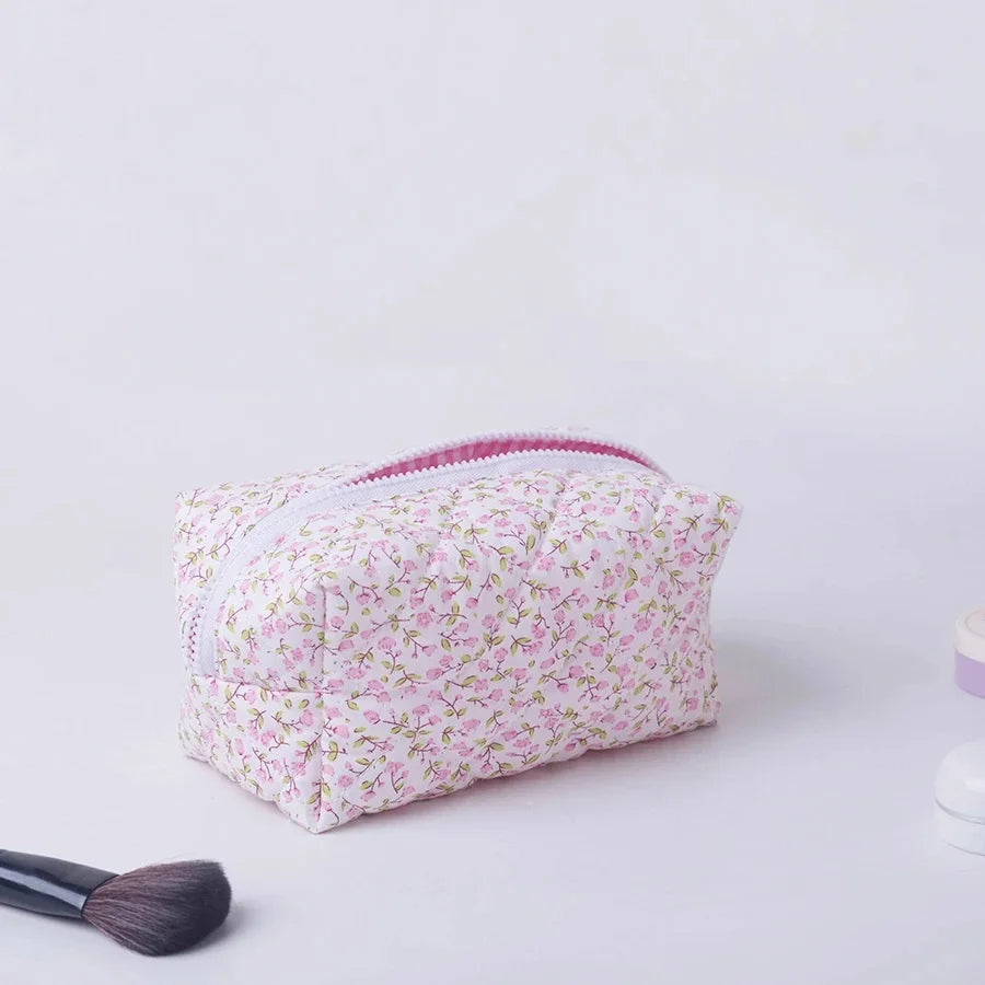 Pink floral padded makeup bag with white zipper, perfect for travel.