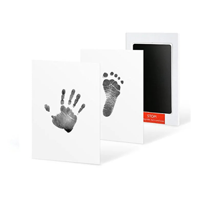 White no-touch ink pad kit for baby hand and foot prints, showing a clear black handprint and footprint.