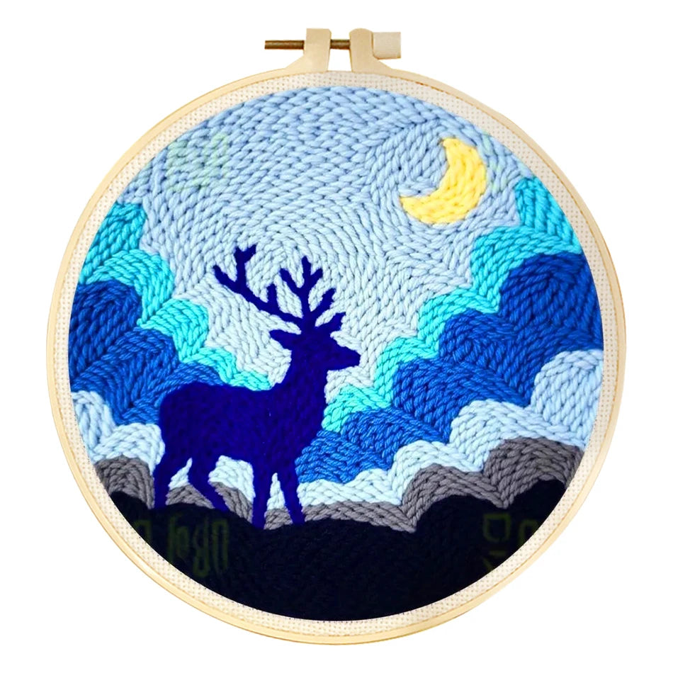 Punch needle embroidery kit featuring a blue deer silhouette against a blue sky with a yellow moon in a wooden hoop.
