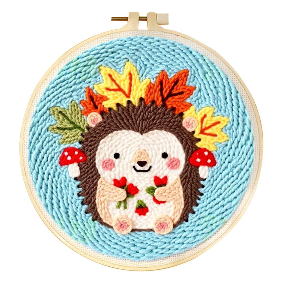 Punch needle embroidery kit featuring a cute hedgehog with autumn leaves and mushrooms on a blue background.
