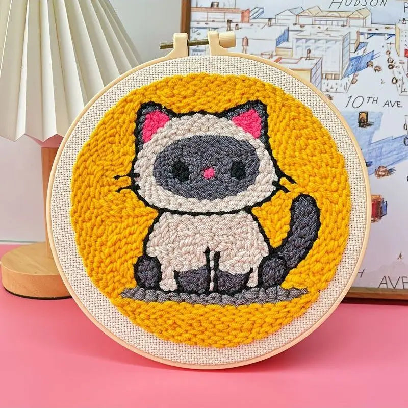 Punch needle embroidery kit featuring a cute Siamese cat on a yellow background, framed in a wooden hoop.