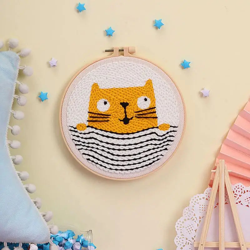 Punch needle embroidery kit with a cute yellow cat in a striped shirt, framed in a wooden hoop.
