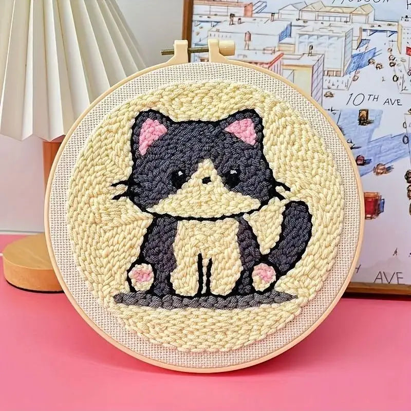 Punch needle embroidery kit with a cute black and white cat design on a light yellow background, framed in a wooden hoop.