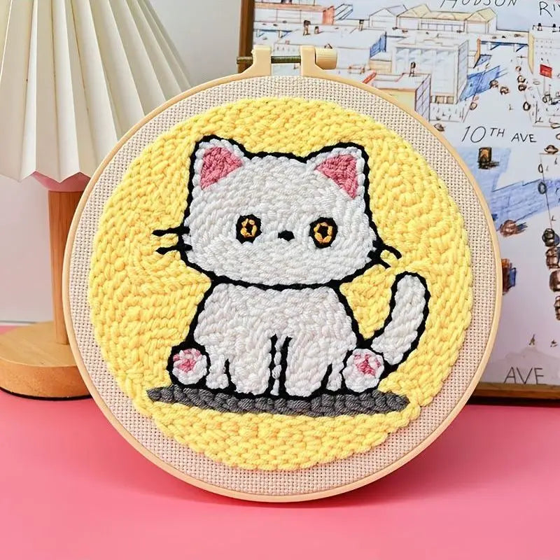 Punch needle embroidery kit featuring a cute white cat on a yellow background, framed in a wooden hoop.