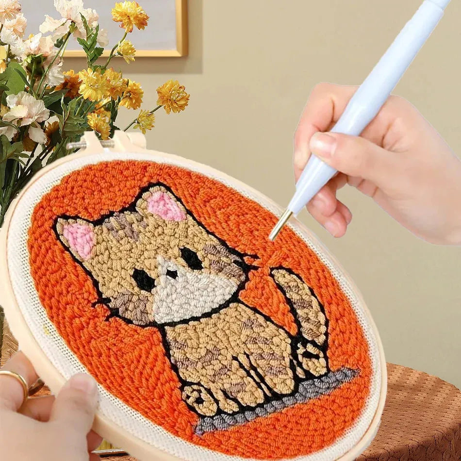 Punch needle embroidery kit with a cute brown cat design on an orange background, held in a wooden hoop.
