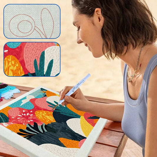 Woman using a punch needle kit to create a colorful abstract floral design on a framed canvas.