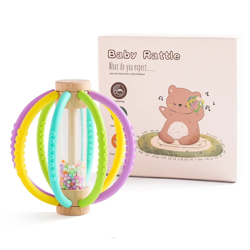 Wooden baby rattle with colorful silicone rings, rain drum, and teether, next to its beige box.