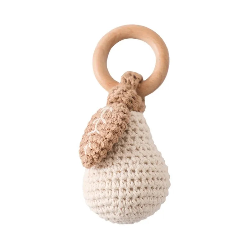 Crochet fruit baby rattle with a natural wooden ring, beige pear, and brown leaf.