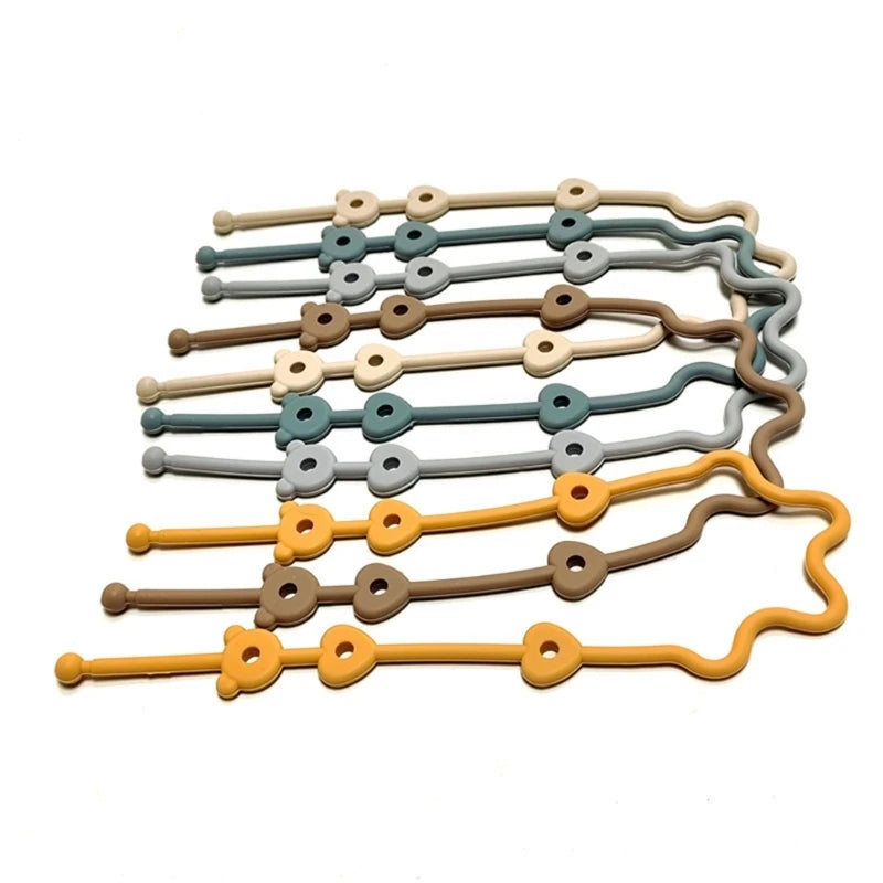 Assorted silicone pacifier and bottle straps in neutral colors like beige, grey, brown, and mustard.
