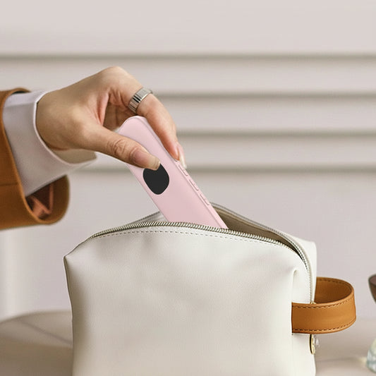 Hand placing a thin, light pink sleep aid speaker with a black button into a white travel pouch.