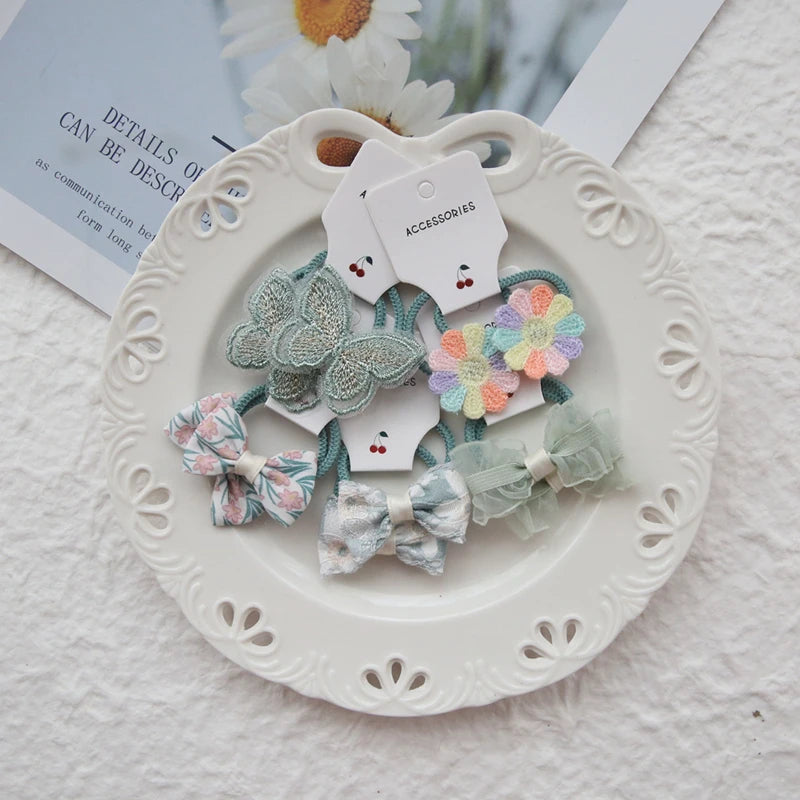 Girls' elastic hair ties with floral, butterfly, and bow designs in various pastel colors.
