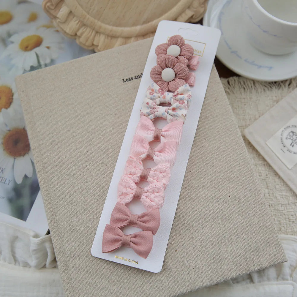 Set of 10 pink fabric hair clips for babies and girls, featuring bows and a flower design.