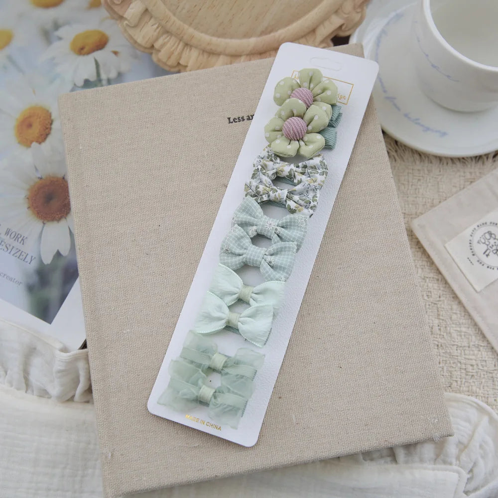 Set of 10 soft green fabric hair clips for babies and girls, featuring bows and flower designs.