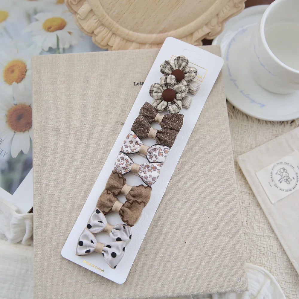 Set of 10 soft fabric hair clips for babies and girls, featuring brown, floral, and polka dot bows.