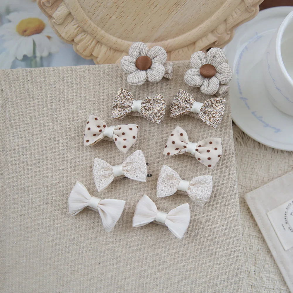Set of 10 beige and brown cotton hair clips for babies, featuring bows and flower designs.