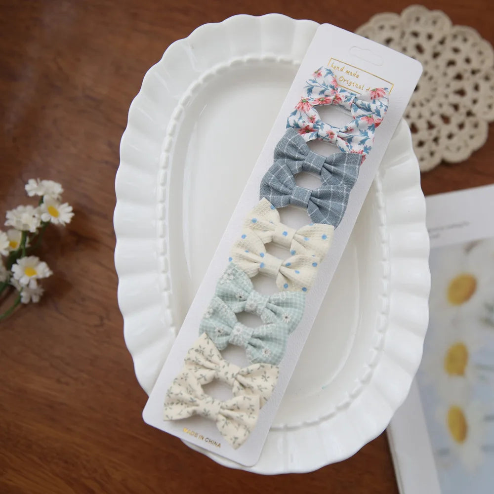 Set of 5 fabric bow hair clips for babies and girls in floral, plaid, and polka dot patterns.