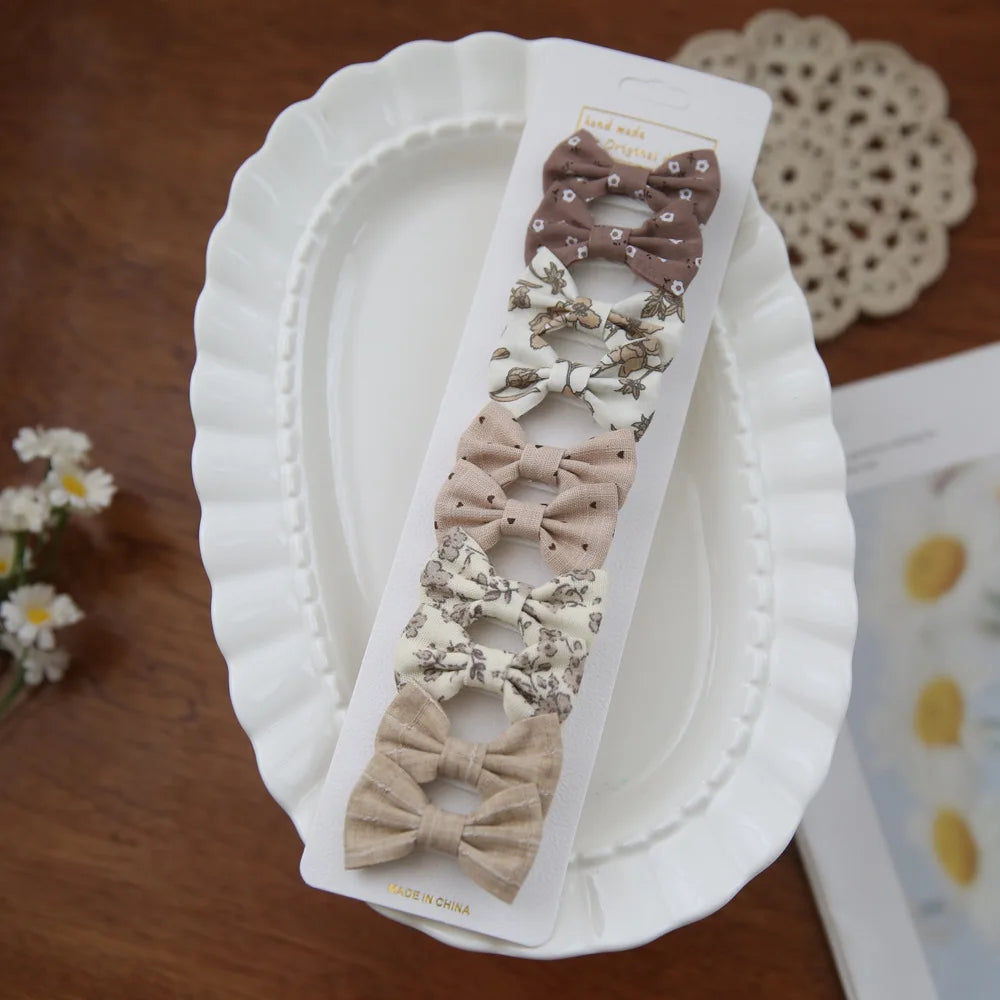 Set of 6 fabric bow hair clips for babies and girls, featuring floral and solid patterns in neutral tones.
