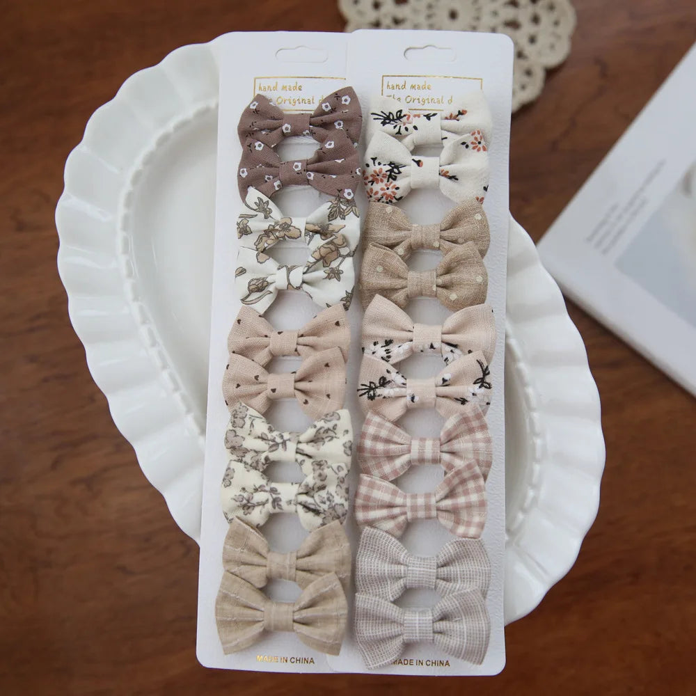 Set of 10 baby and toddler hair clips with fabric bows in various neutral colors and patterns.