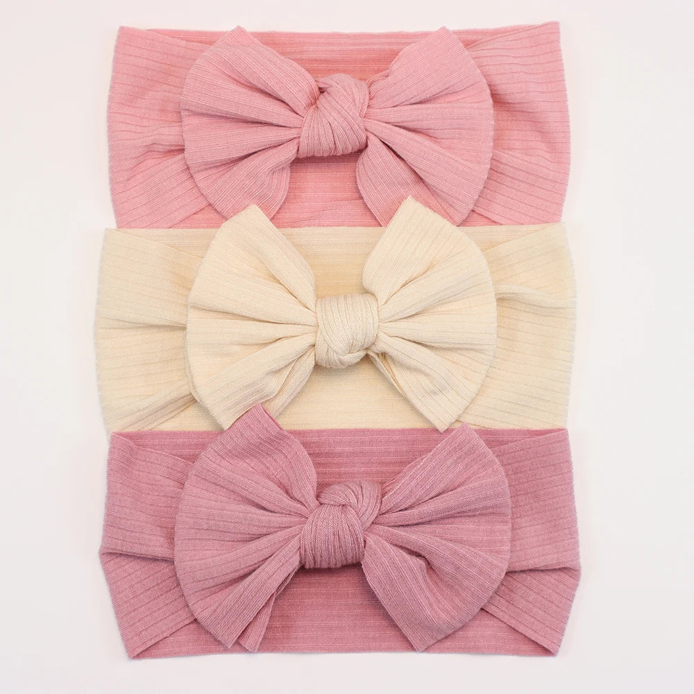 Set of 3 soft nylon baby headbands with bows in pink, cream, and dusty rose.
