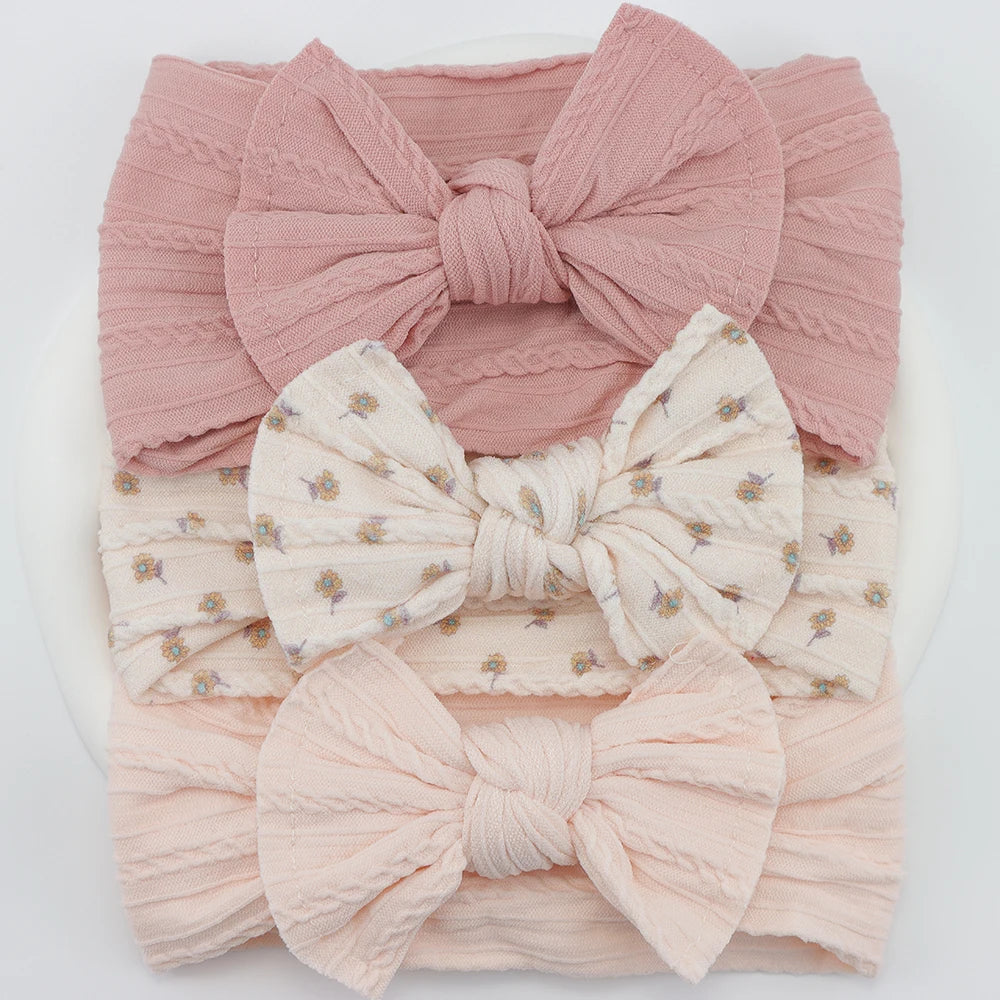 Set of 3 soft, flexible nylon baby headbands with bows: pink, floral cream, and light pink.