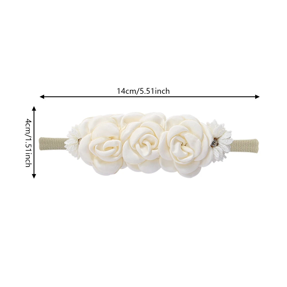 Soft nylon baby headband with three white floral rosettes and small white accent flowers, 14cm long.