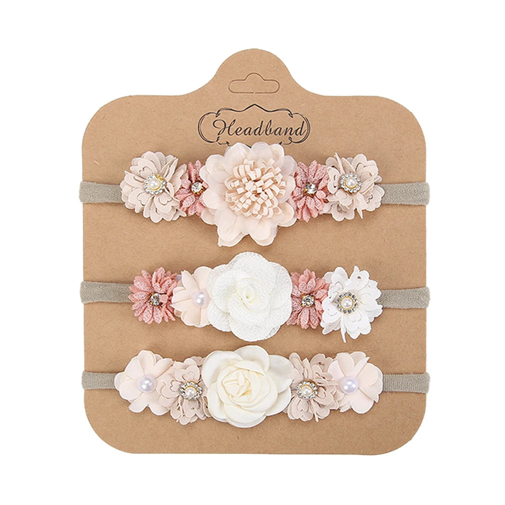 Set of 3 soft nylon baby headbands with delicate pink, white, and beige floral designs.