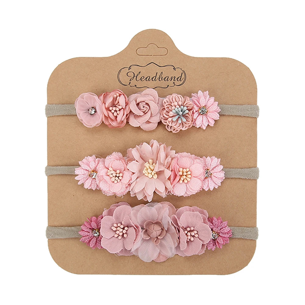 Set of 3 soft nylon baby headbands with various pink floral designs on a brown card.