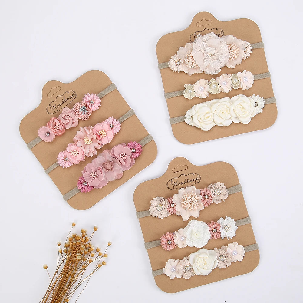 Set of 3 soft nylon baby headbands with delicate pink, white, and cream floral designs.