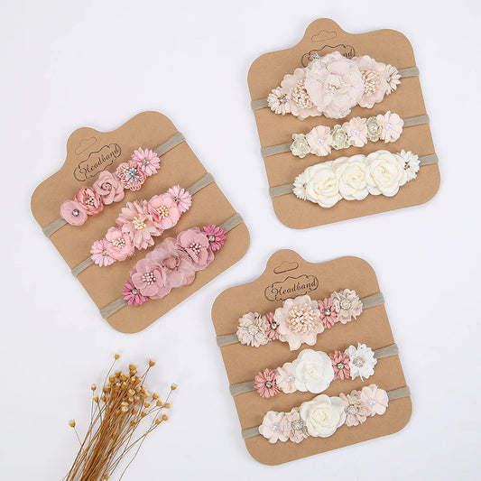 Set of 3 soft nylon baby headbands with delicate pink, white, and cream floral designs.
