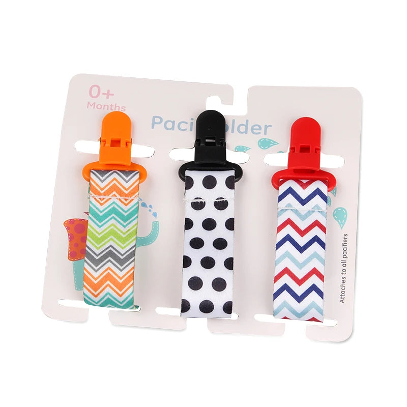 Set of 3 colorful fabric pacifier clips with plastic clasps, featuring zigzag and polka dot patterns.