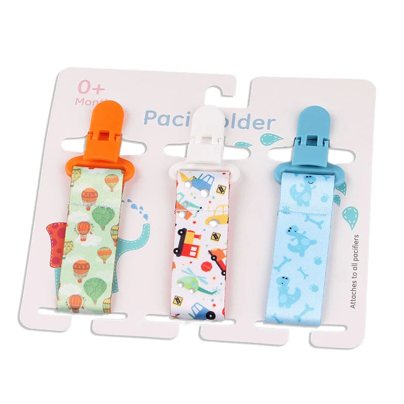 Set of 3 baby pacifier clips with colorful fabric straps and plastic clasps, featuring hot air balloons, cars, and dinosaurs.