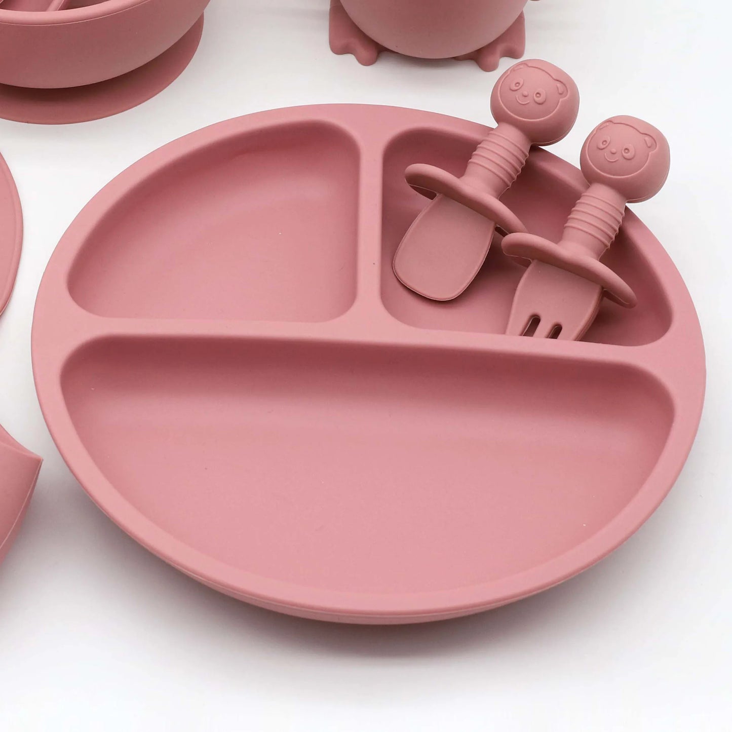 Pink silicone baby feeding set with divided suction plate, spoon, and fork.