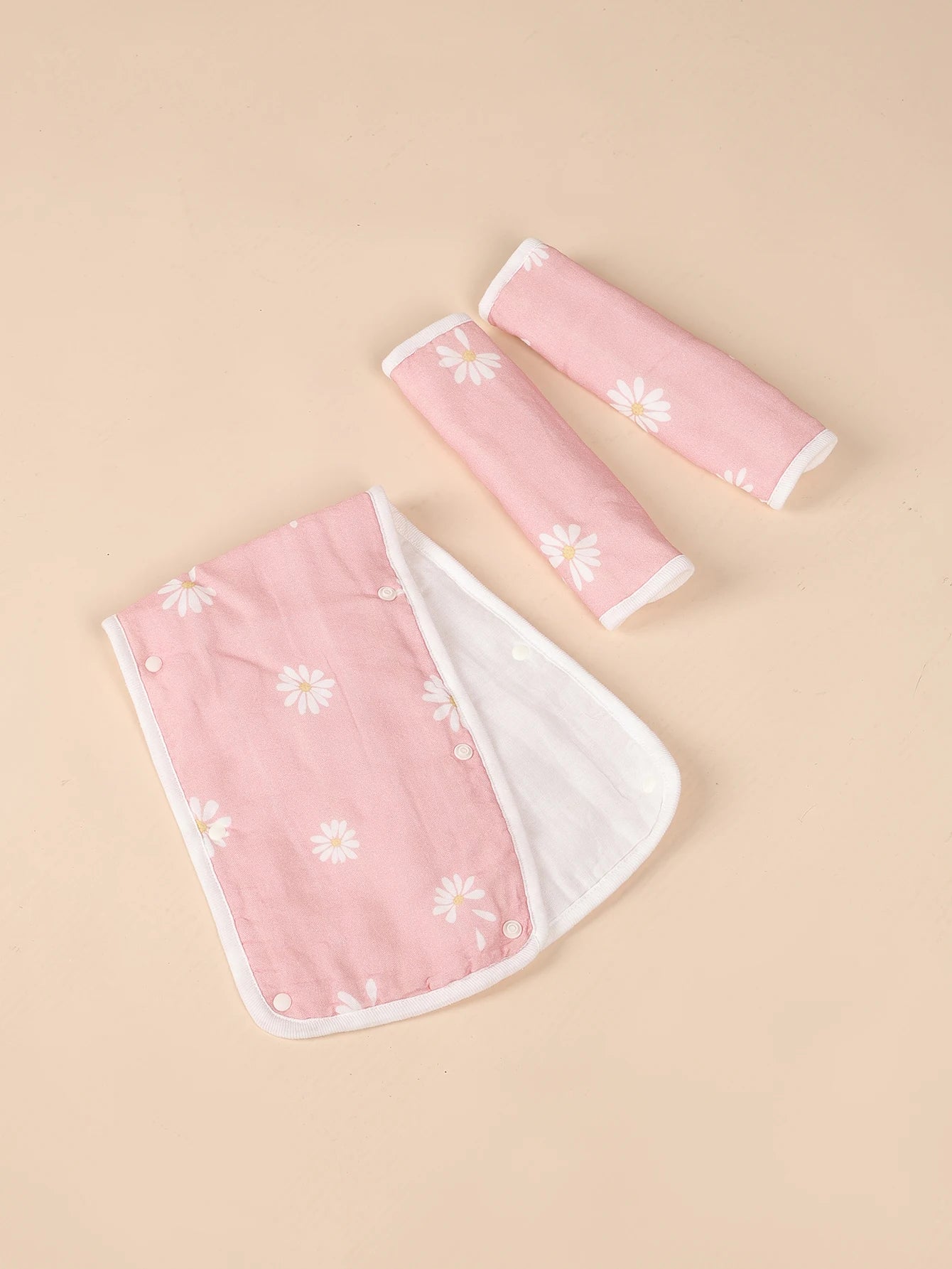 Pink baby stroller handle cover and seat belt pads with white daisy print.