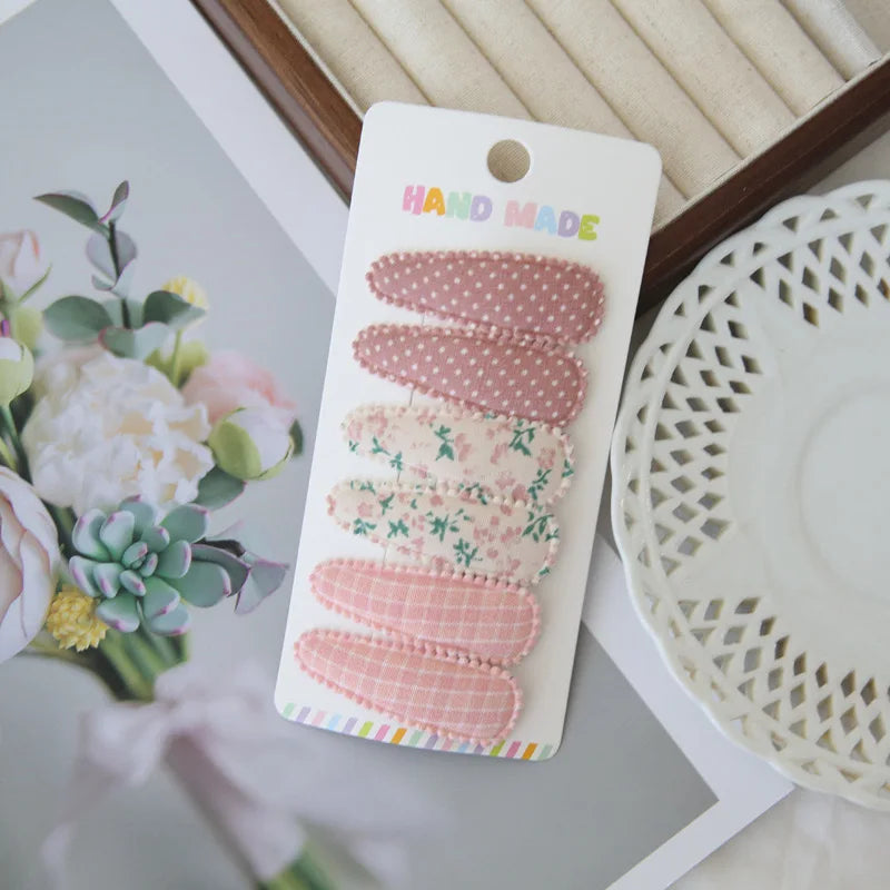Set of 6 handmade pink floral and polka dot fabric snap hair clips for girls.