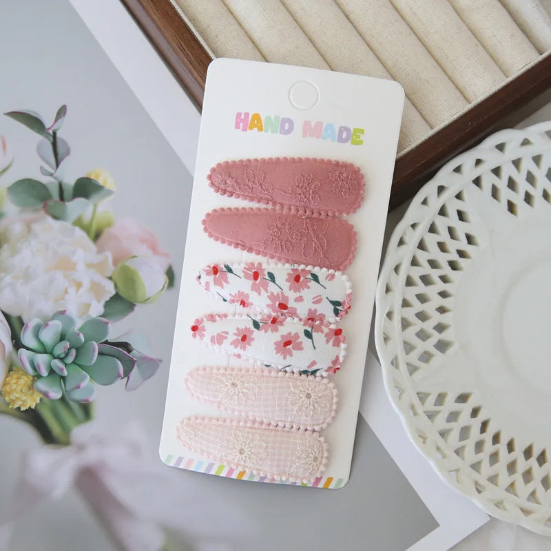 Set of 6 handmade floral snap hair clips for girls, featuring pink, white, and patterned designs.