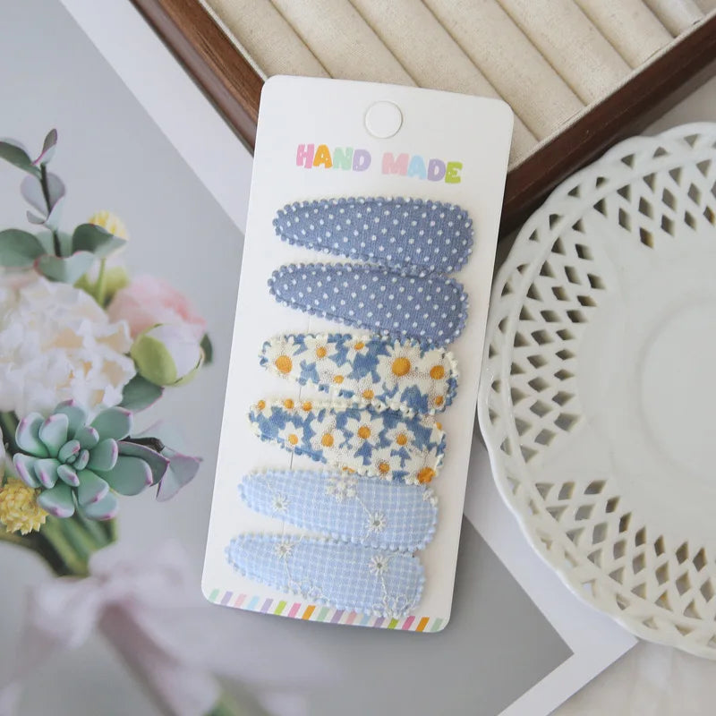 Set of 6 handmade blue cotton snap hair clips for girls, featuring polka dot, daisy, and checkered floral designs.