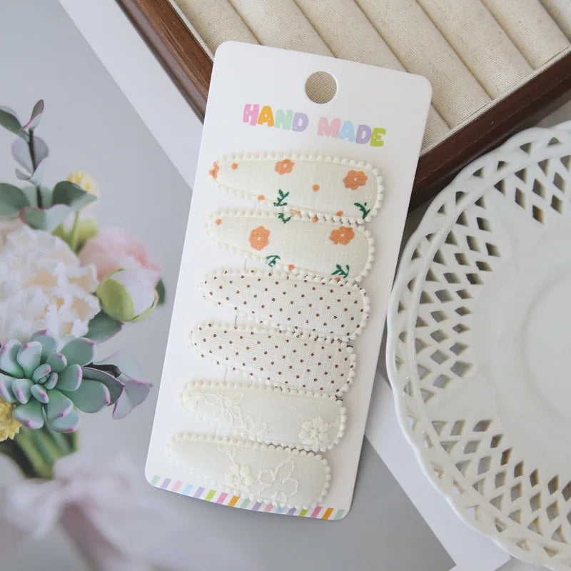 Set of 6 handmade floral snap hair clips for girls, featuring varied patterns like flowers, polka dots, and lace.