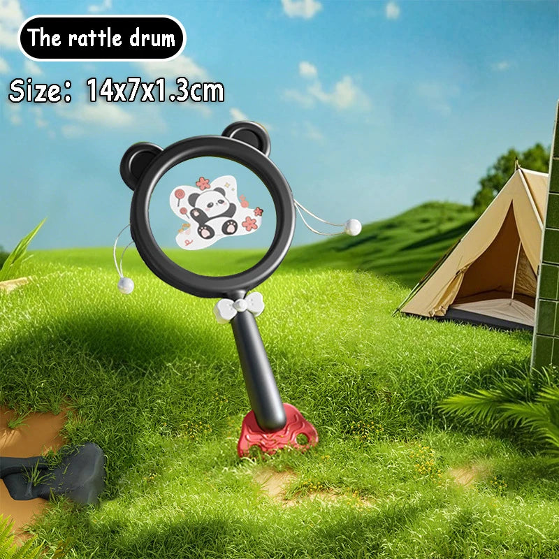 Black panda rattle drum with a cute panda design, red base, and white beads, set outdoors.
