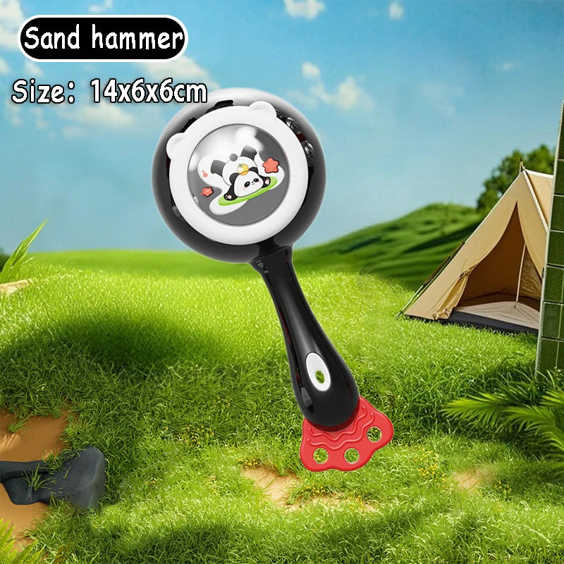 Black and white Montessori musical rattle with panda design, red textured base, on green grass.