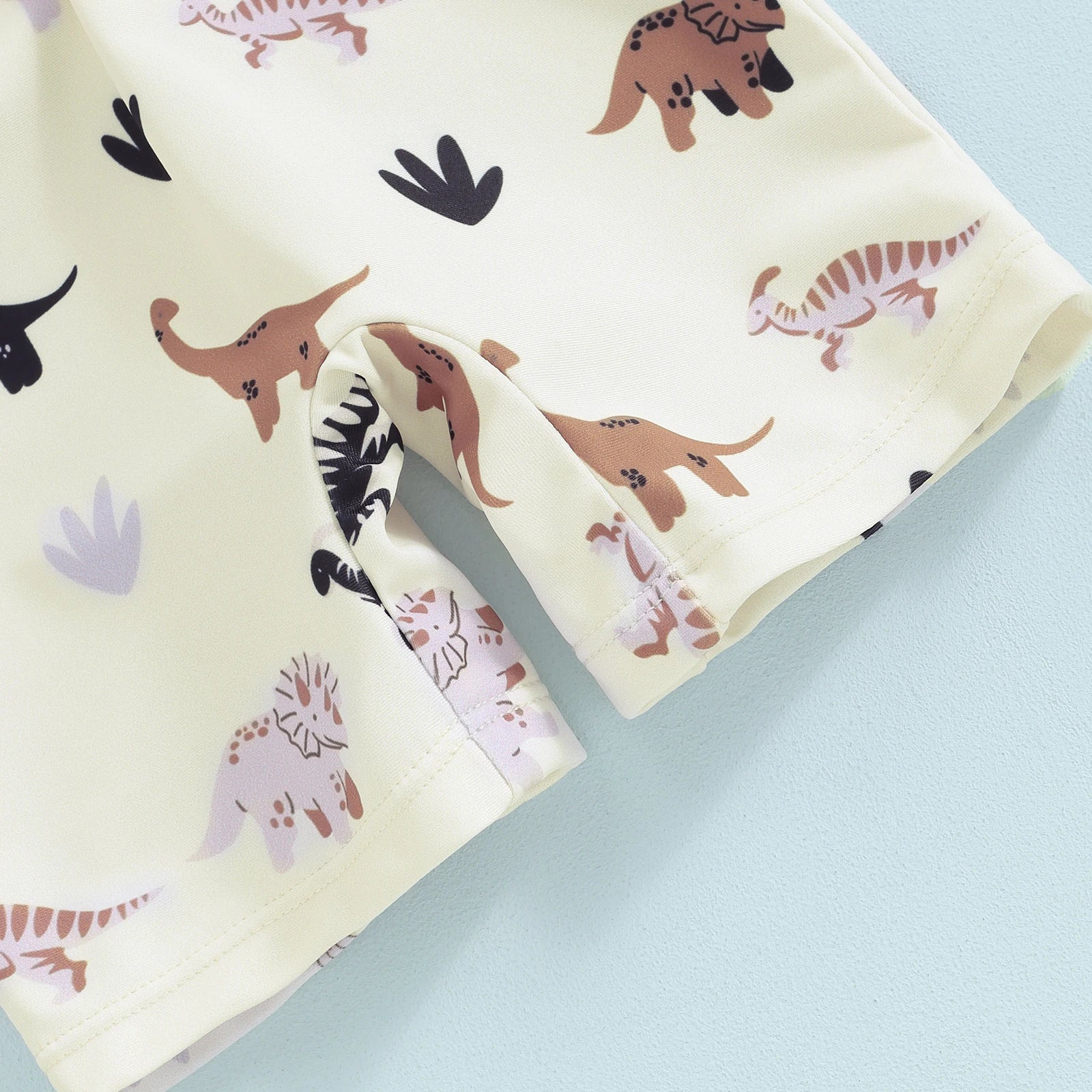 Baby long-sleeve swimsuit in light yellow with brown and purple dinosaur print.