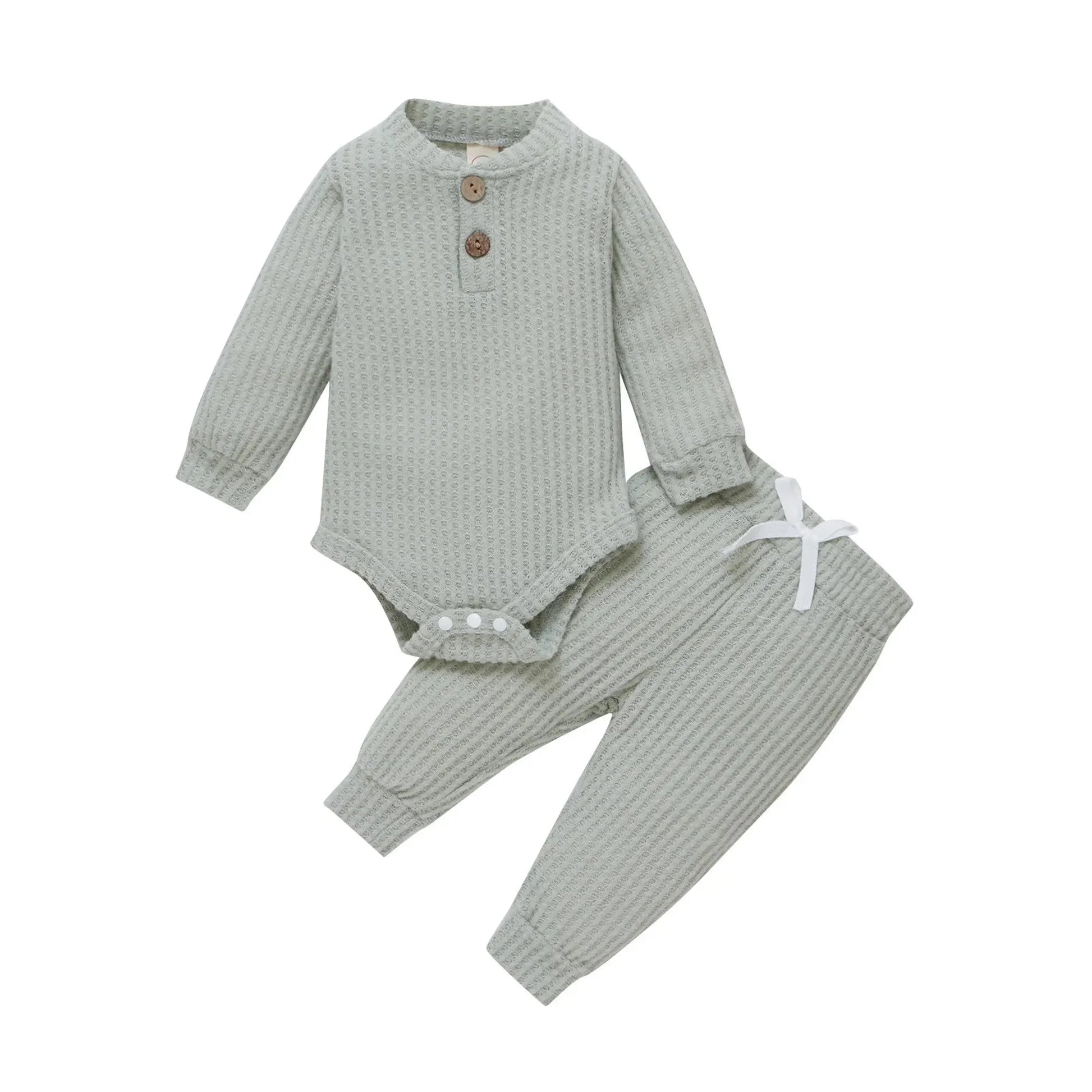 Sage green waffle knit long-sleeve baby bodysuit and matching pants with wooden buttons and white drawstring.